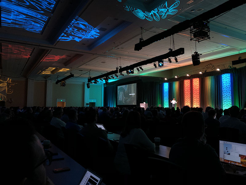 Photo of audience with keynote speaker during the conference in a dim setting